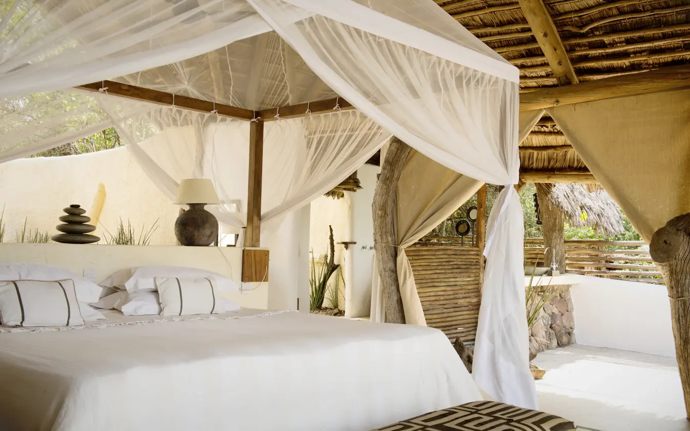 Luxury safari bedroom with flowing white canopy curtains and thatched roof, Kiba Point, Nyerere National Park, Tanzania