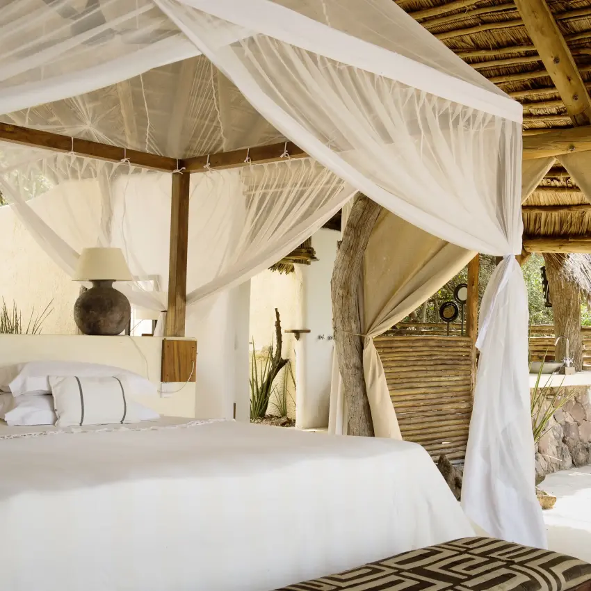 Luxury safari bedroom with flowing white canopy curtains and thatched roof, Kiba Point, Nyerere National Park, Tanzania