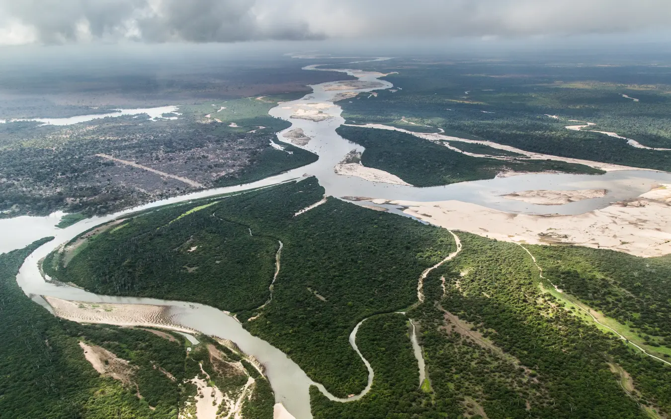 Aerial view of meandering river through rainforest with cleared settlements, Kiba Point, Nyerere National Park, Tanzania