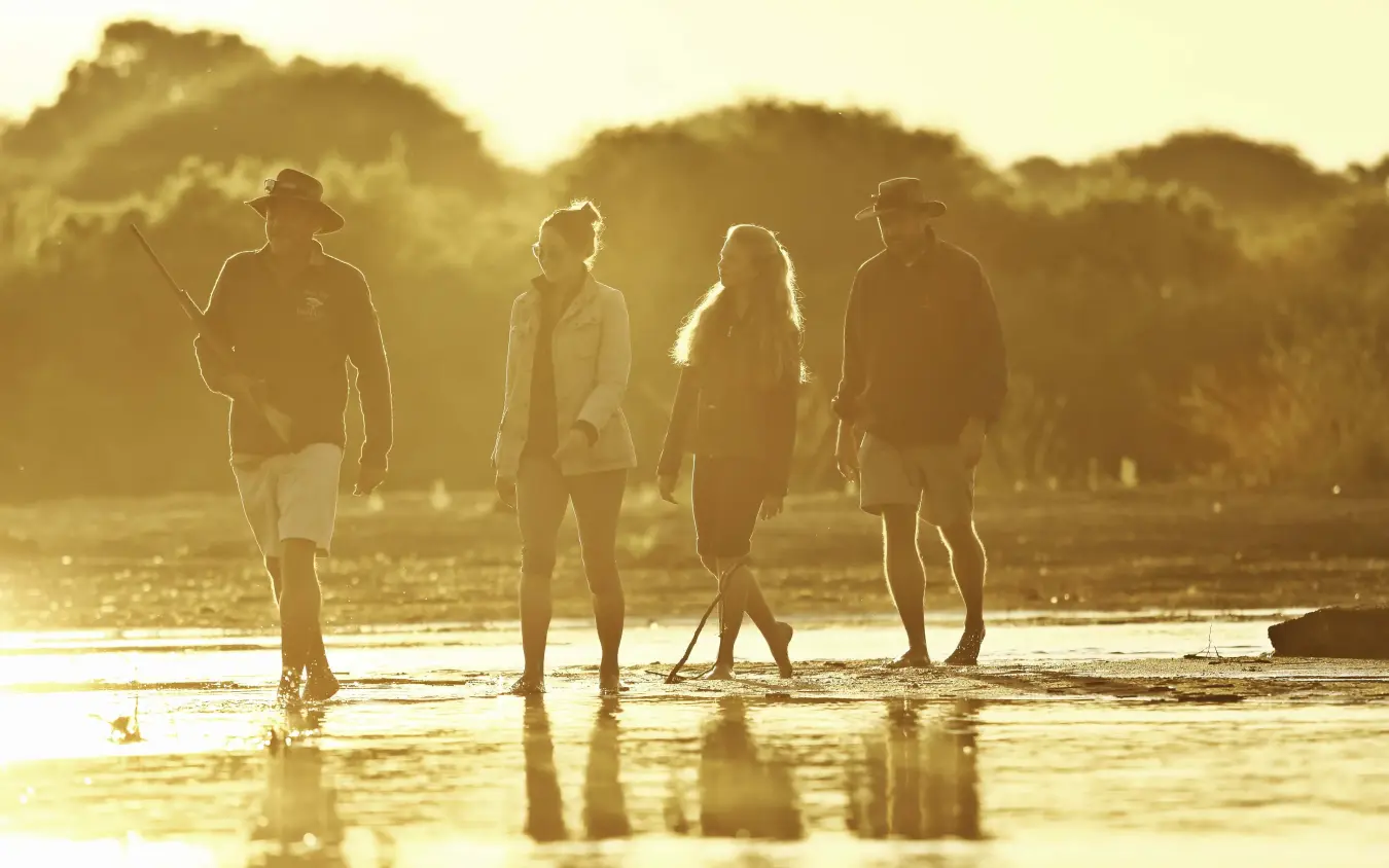 Group of guests wading together in shallow water at sunset, Tanzania
