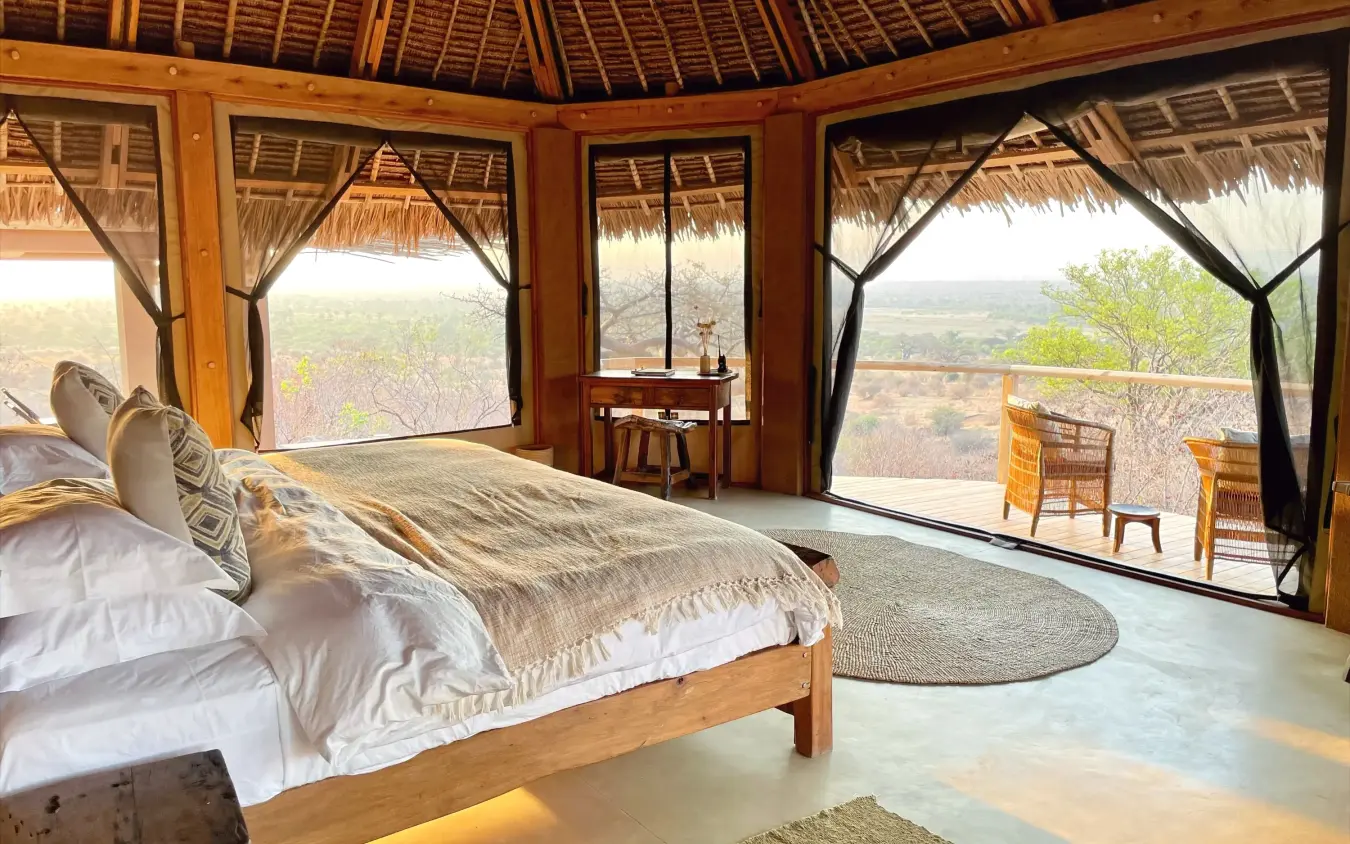 Bedroom with expansive windows overlooking savanna landscape, Kichaka Expeditions, Ruaha National Park, Tanzania