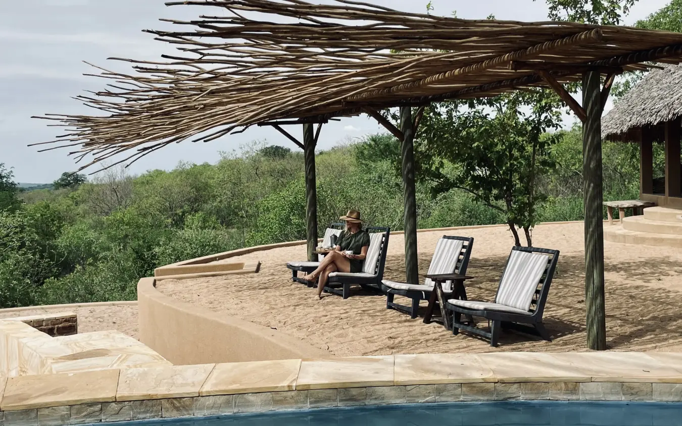 Pool deck with thatched pergola and lounge chairs overlooking savanna, Kichaka Expeditions, Ruaha National Park, Tanzania