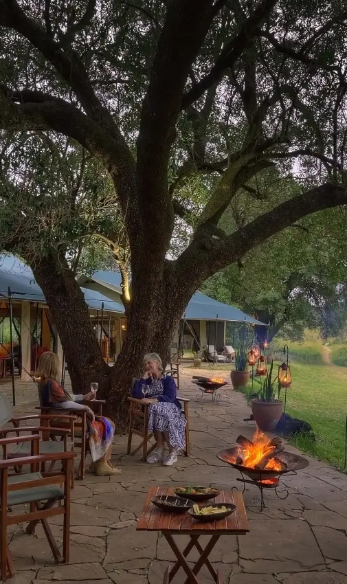 Open-air dining area with fire pit under large tree, Kicheche Bush Olare, Maasai Mara, Kenya
