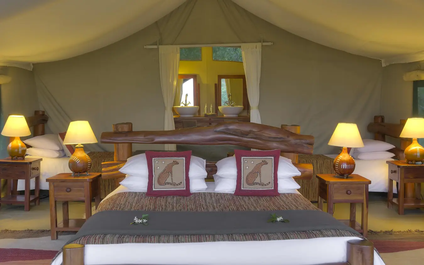 Luxury safari tent bedroom with wooden furnishings and lamp lighting, Kicheche Mara North, Maasai Mara, Kenya