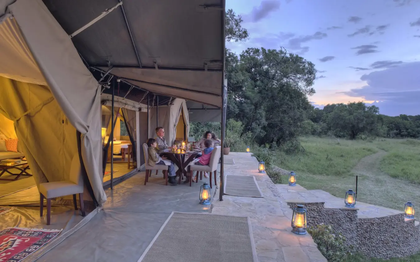 Luxury safari tent with guests dining at dusk overlooking savanna, Kicheche Mara North, Maasai Mara, Kenya