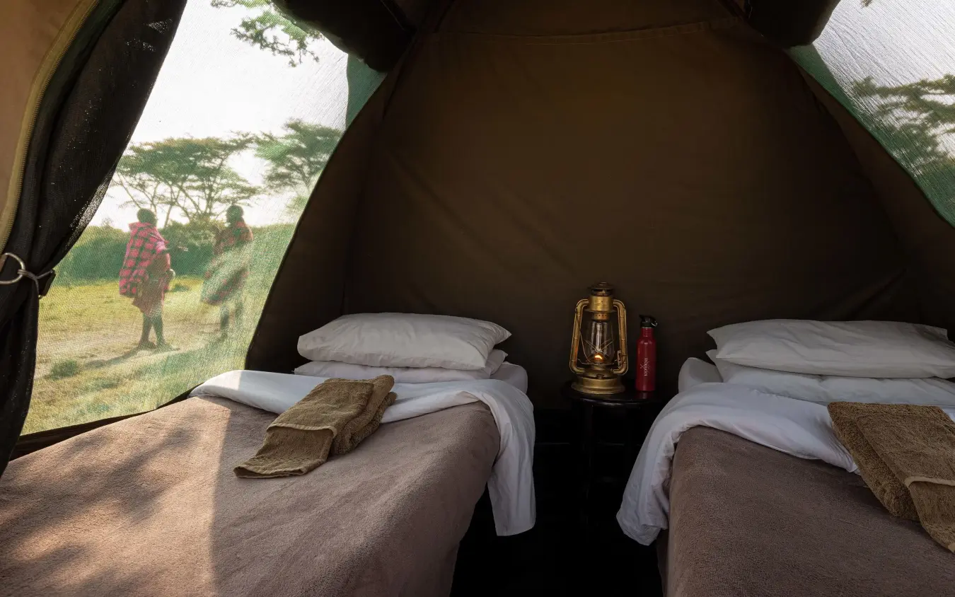 Interior of safari tent with two beds and open canvas flaps, Kicheche Valley Naboisho, Maasai Mara, Kenya