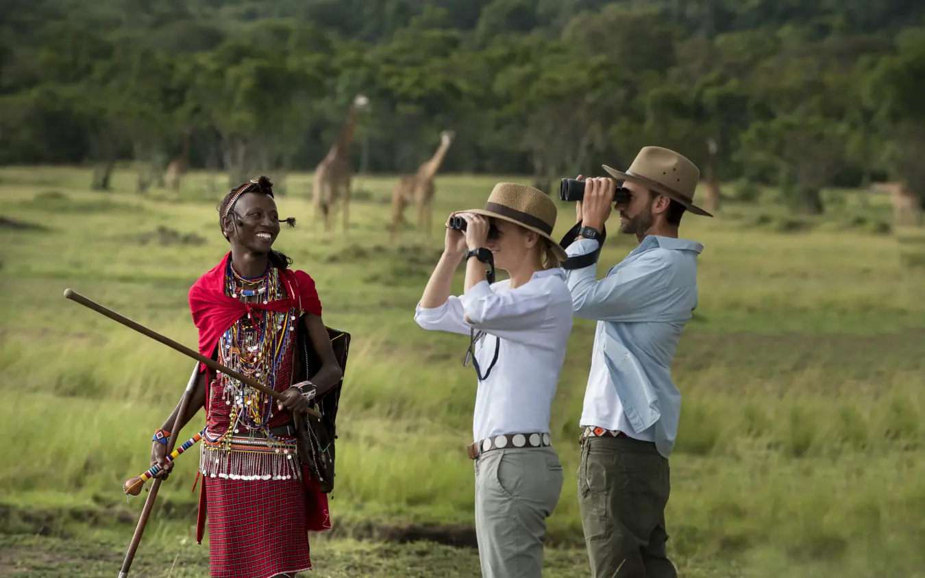 Local guide with tourists using binoculars on savanna game drive, Kichwa Tembo Tented Camp, Maasai Mara, Kenya