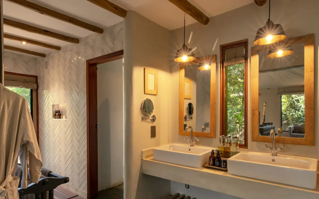 Modern bathroom with dual vanities and pendant lighting overlooking forest, Kichwa Tembo Tented Camp, Maasai Mara, Kenya