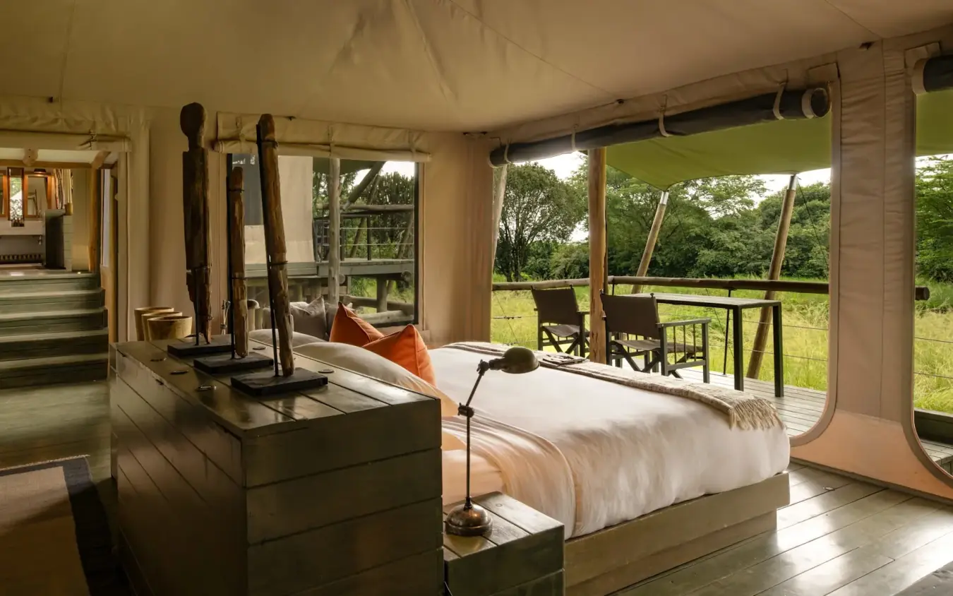 Luxury safari bedroom with four-poster bed overlooking grassland savanna, Kichwa Tembo Tented Camp, Maasai Mara, Kenya