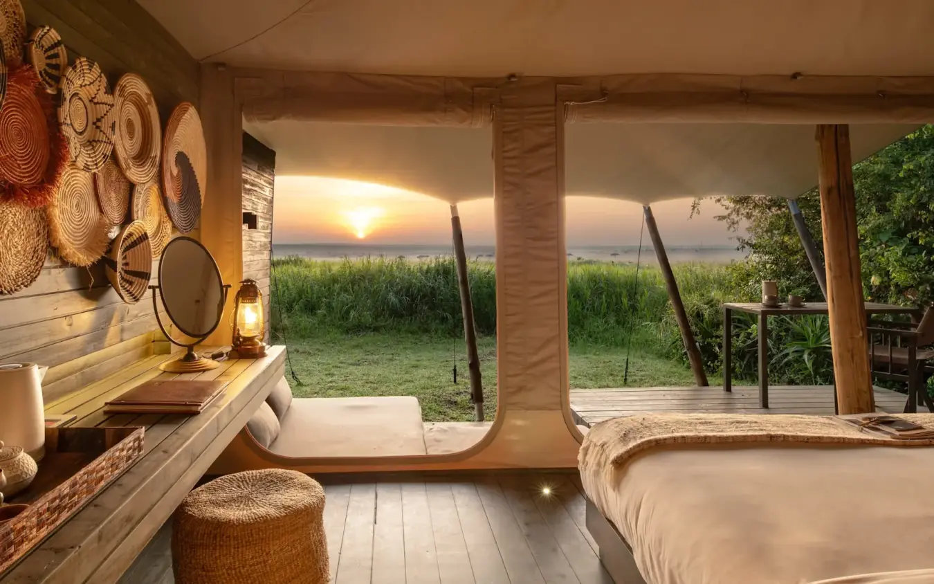 Luxury safari tent interior with bed and vanity overlooking wetland at sunset, Kichwa Tembo Tented Camp, Maasai Mara, Kenya