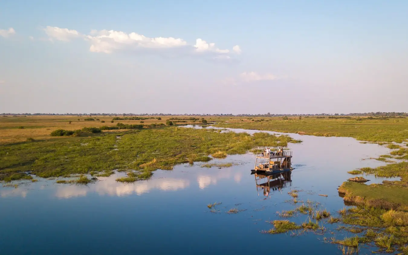 Motorboat navigating shallow waterways through vast wetland landscape, King’s Pool, Linyanti Wildlife Reserve, Botswana