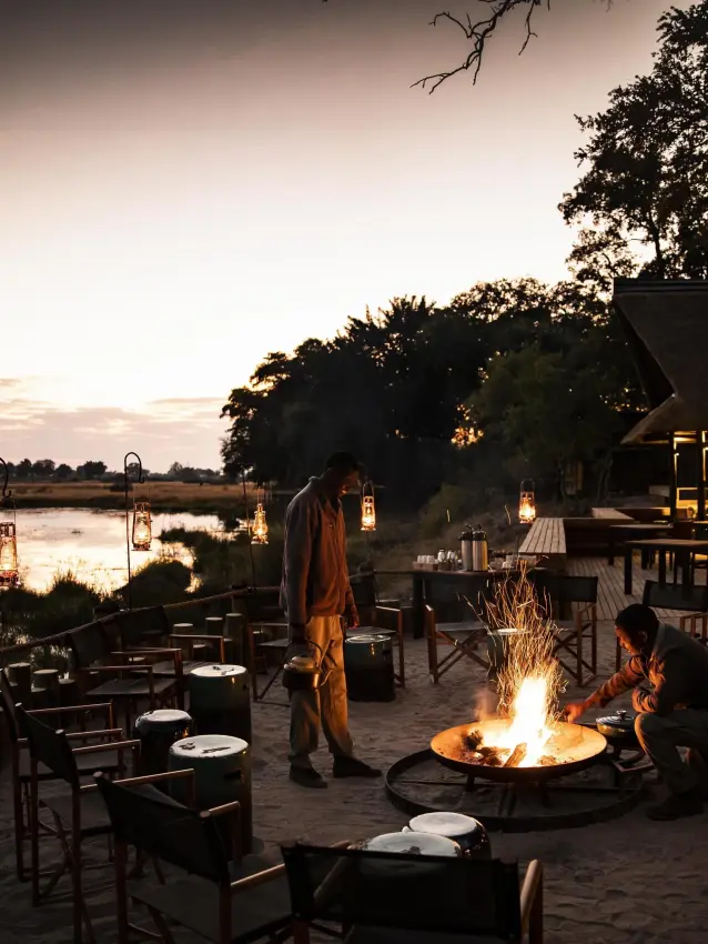Riverside fire pit seating area at dusk with water view, King’s Pool, Linyanti Wildlife Reserve, Botswana