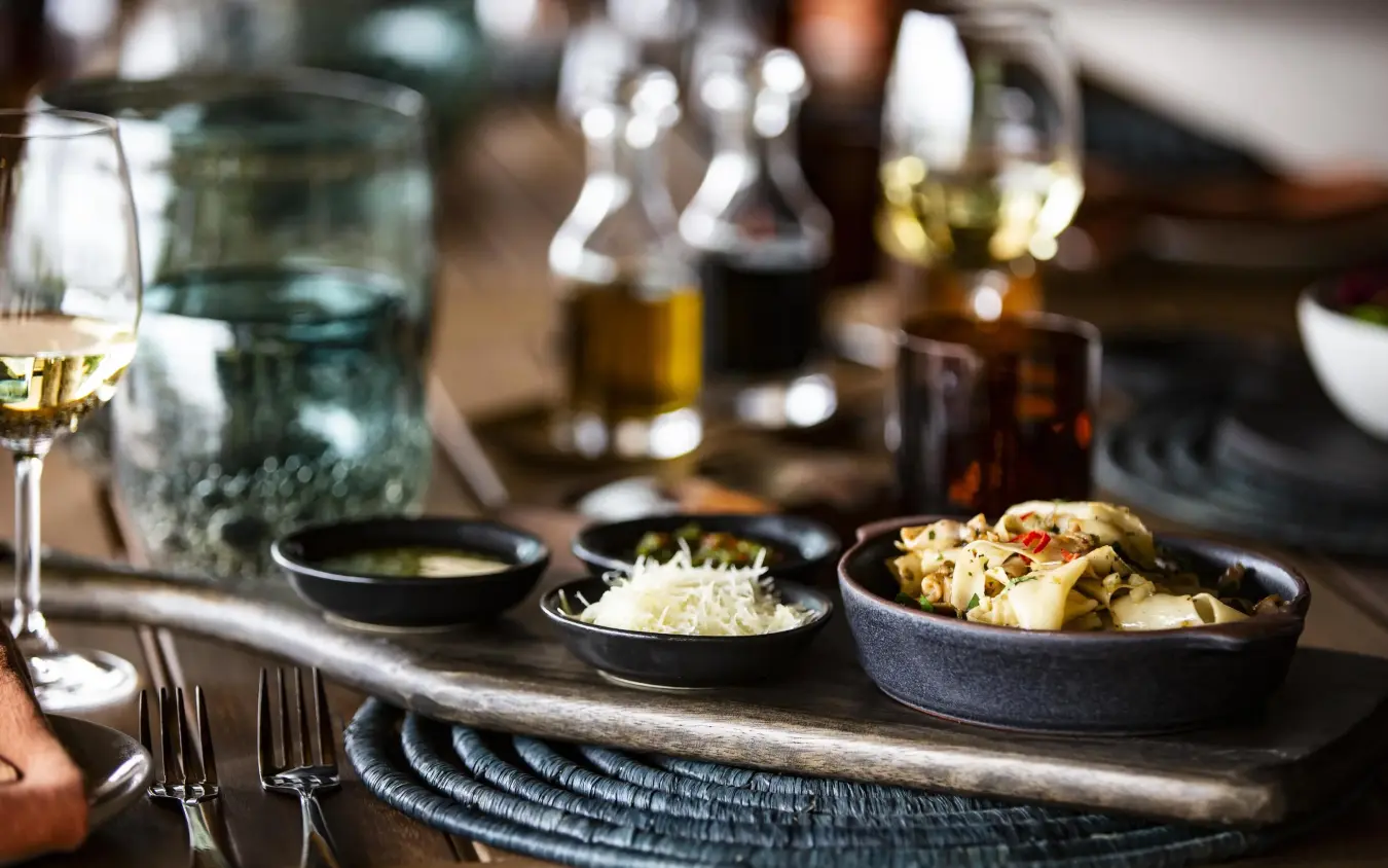 Plated dishes and wine glasses on dining table, King’s Pool, Linyanti Wildlife Reserve, Botswana