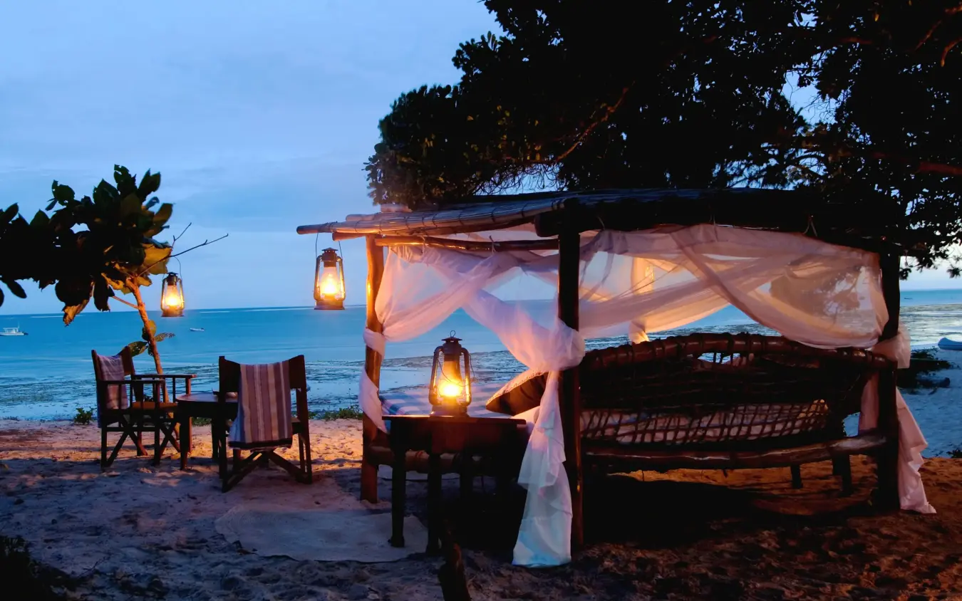 Beachfront cabana with lanterns and draped fabric at dusk overlooking ocean, Kinondo Kwetu, Diani Beach, Kenya