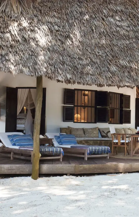 Beach bungalow with thatched roof and blue striped loungers on sand, Kinondo Kwetu, Diani Beach, Kenya