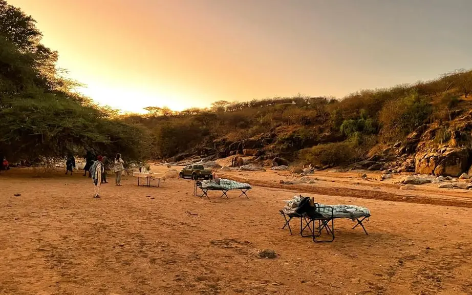 Camping setup at sunset in sandy riverbed valley, Kenya