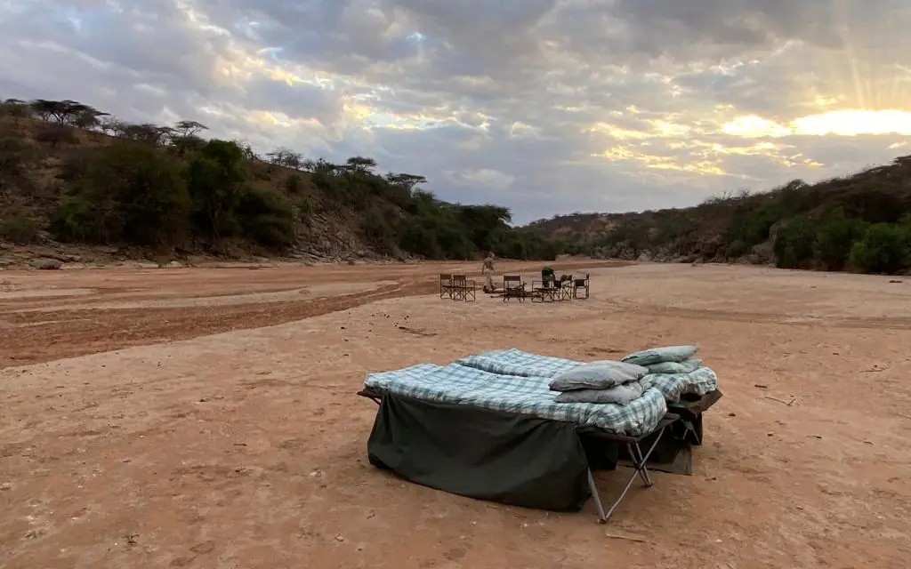Camp bed setup in dry riverbed at sunset, Kitich Camp, Northern Kenya, Kenya