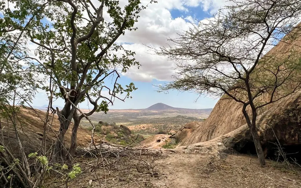 Rocky gorge with distant volcano and sparse vegetation, Kitich Camp, Northern Kenya, Kenya
