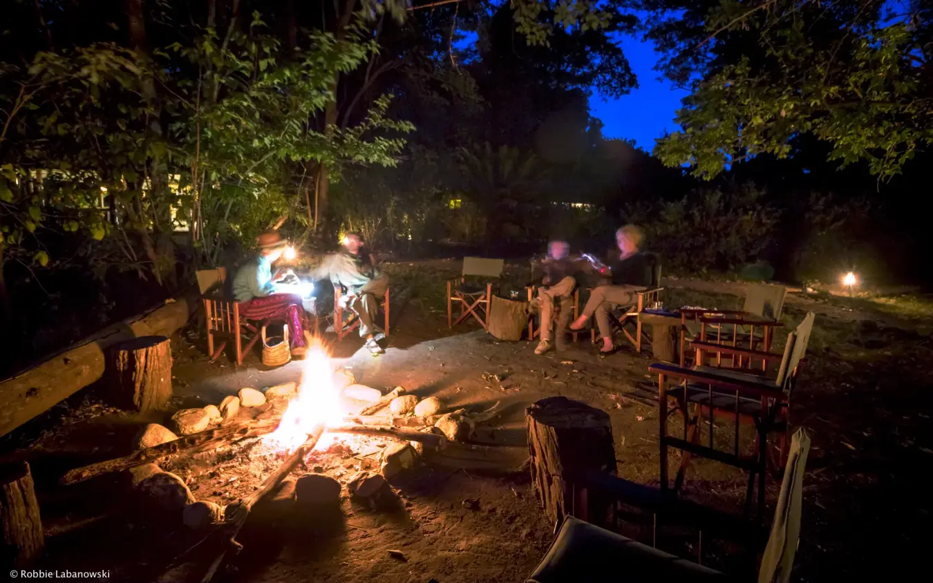 Guests gathered around campfire under starlit sky at night, Kitich Camp, Northern Kenya, Kenya