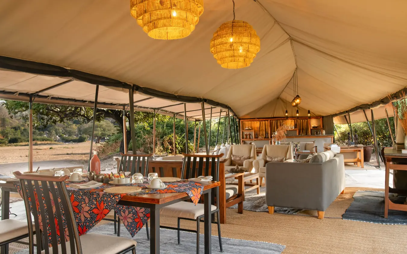 Open-air tent lounge with dining and seating areas, Kokoko Camp, Ruaha National Park, Tanzania