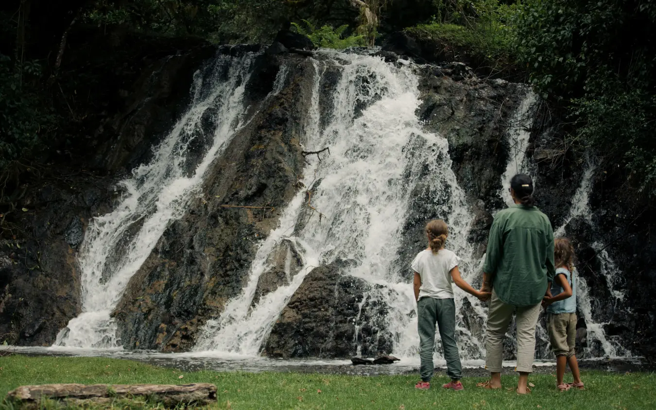 Family viewing waterfall from grassy clearing below, Koroi Forest Camp, Arusha, Tanzania