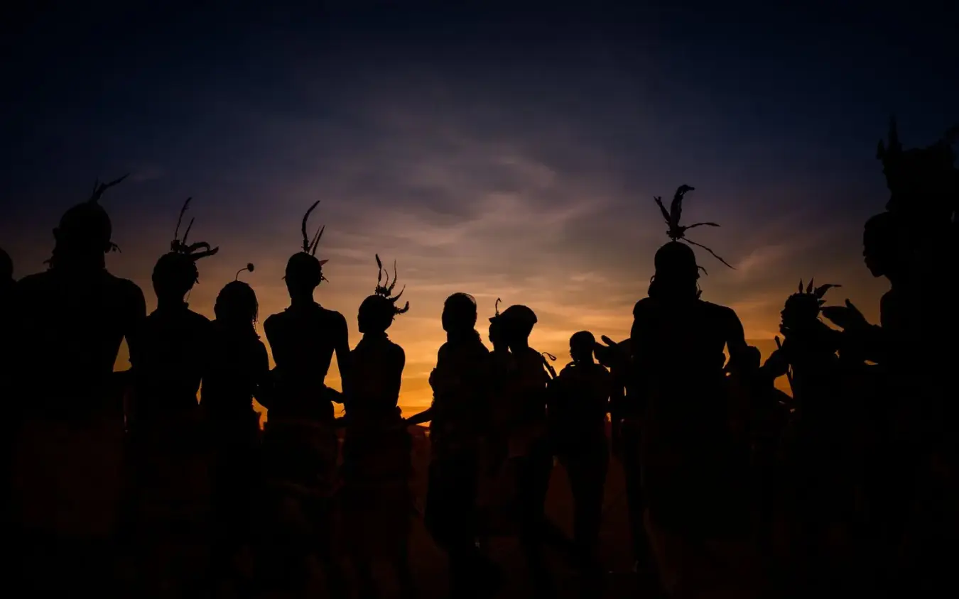 Group of people silhouetted against sunset sky with headdresses, Koros Camp, Northern Kenya, Kenya