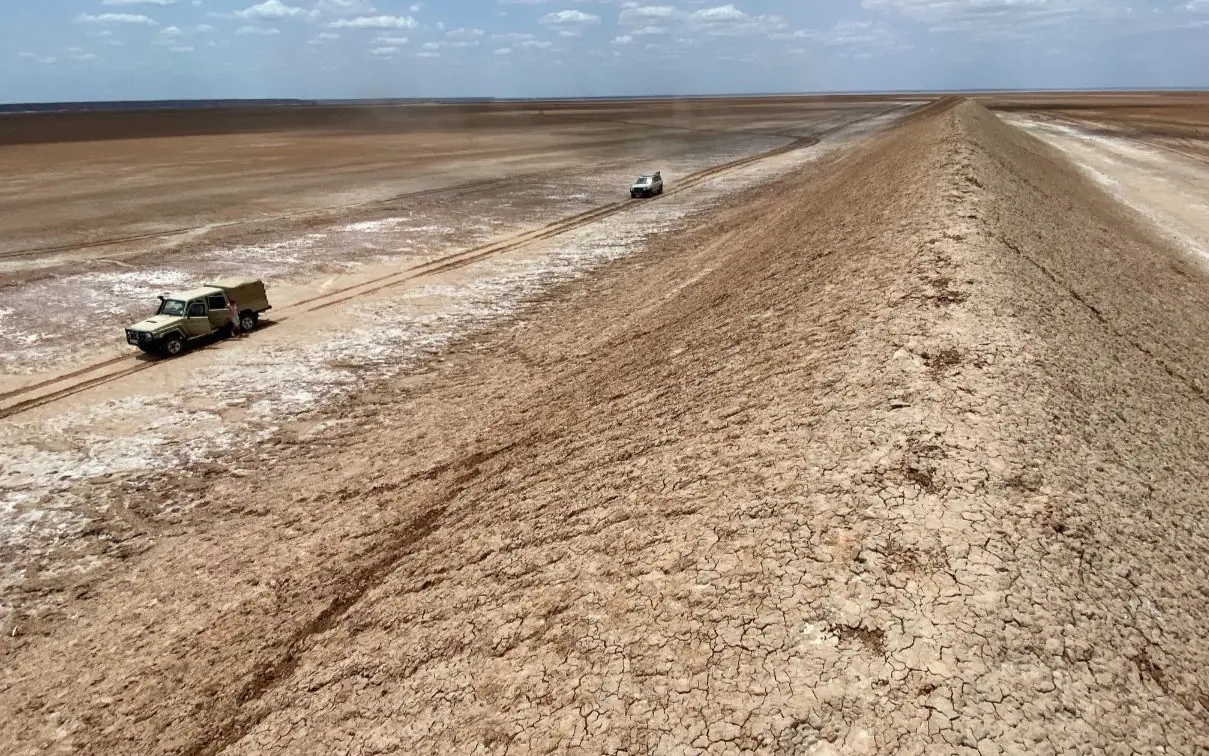Vehicles traveling across arid desert landscape during dry season, Koros Camp, Northern Kenya, Kenya