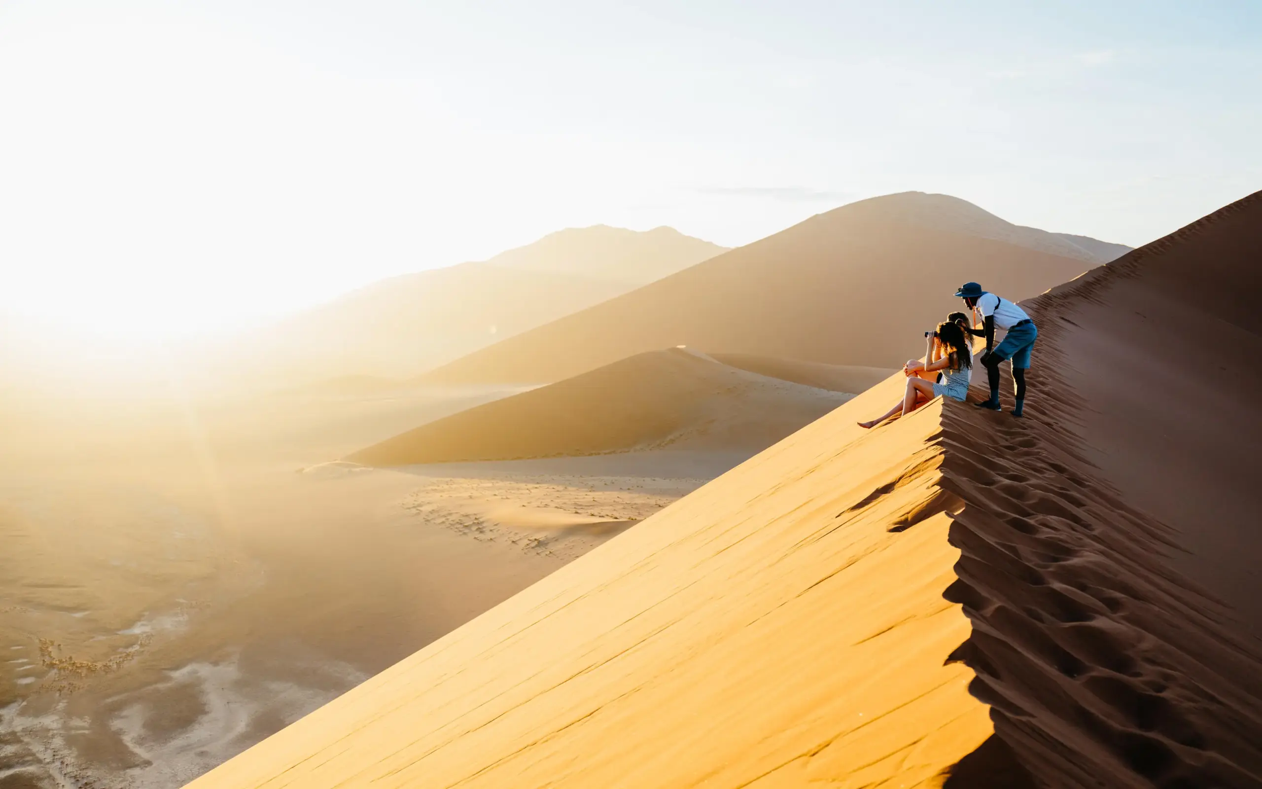 Guests hiking on desert sand dune at sunrise, Kulala Desert Lodge, Sossusvlei, Namibia
