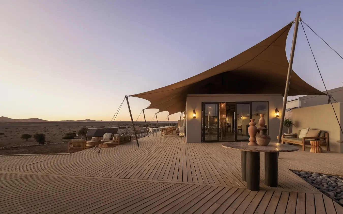 Desert lodge with wooden deck and draped sail canopy at dusk, Kulala Desert Lodge, Sossusvlei, Namibia