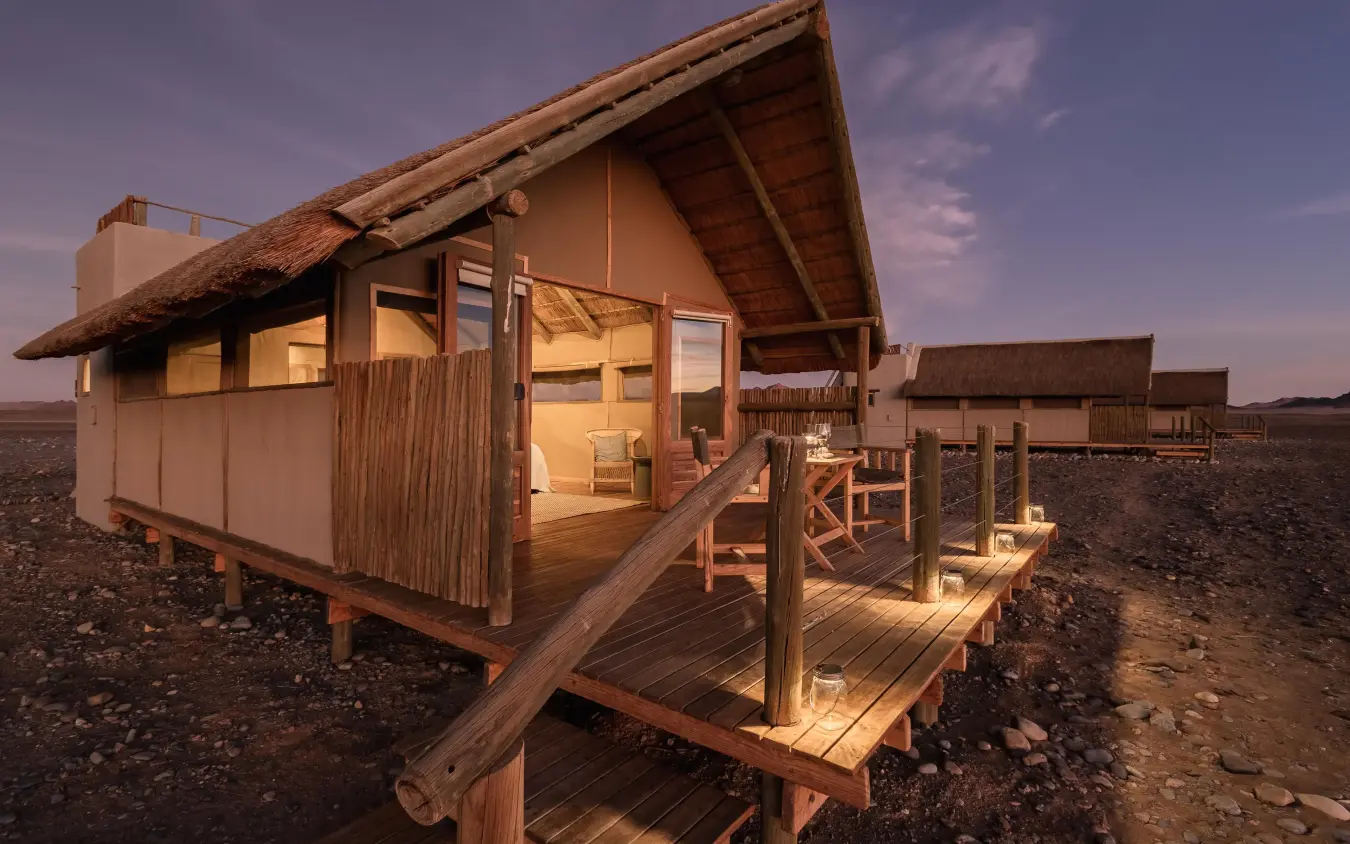 Thatched roof cabin with wooden deck at dusk, Kulala Desert Lodge, Sossusvlei, Namibia