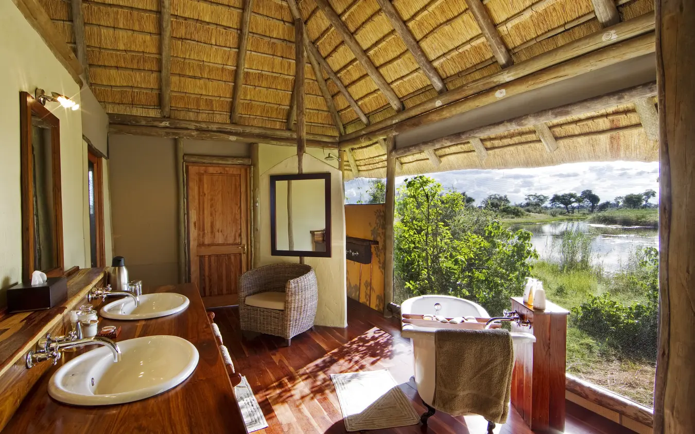 Luxury bathroom with dual sinks and soaking tub overlooking river wetland landscape, Kwando Lagoon Camp, Linyanti Wildlife Reserve, Botswana