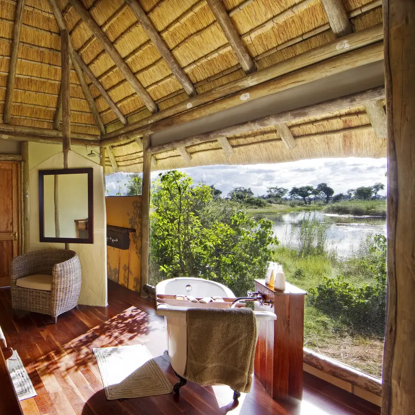 Luxury bathroom with dual sinks and soaking tub overlooking river wetland landscape, Kwando Lagoon Camp, Linyanti Wildlife Reserve, Botswana