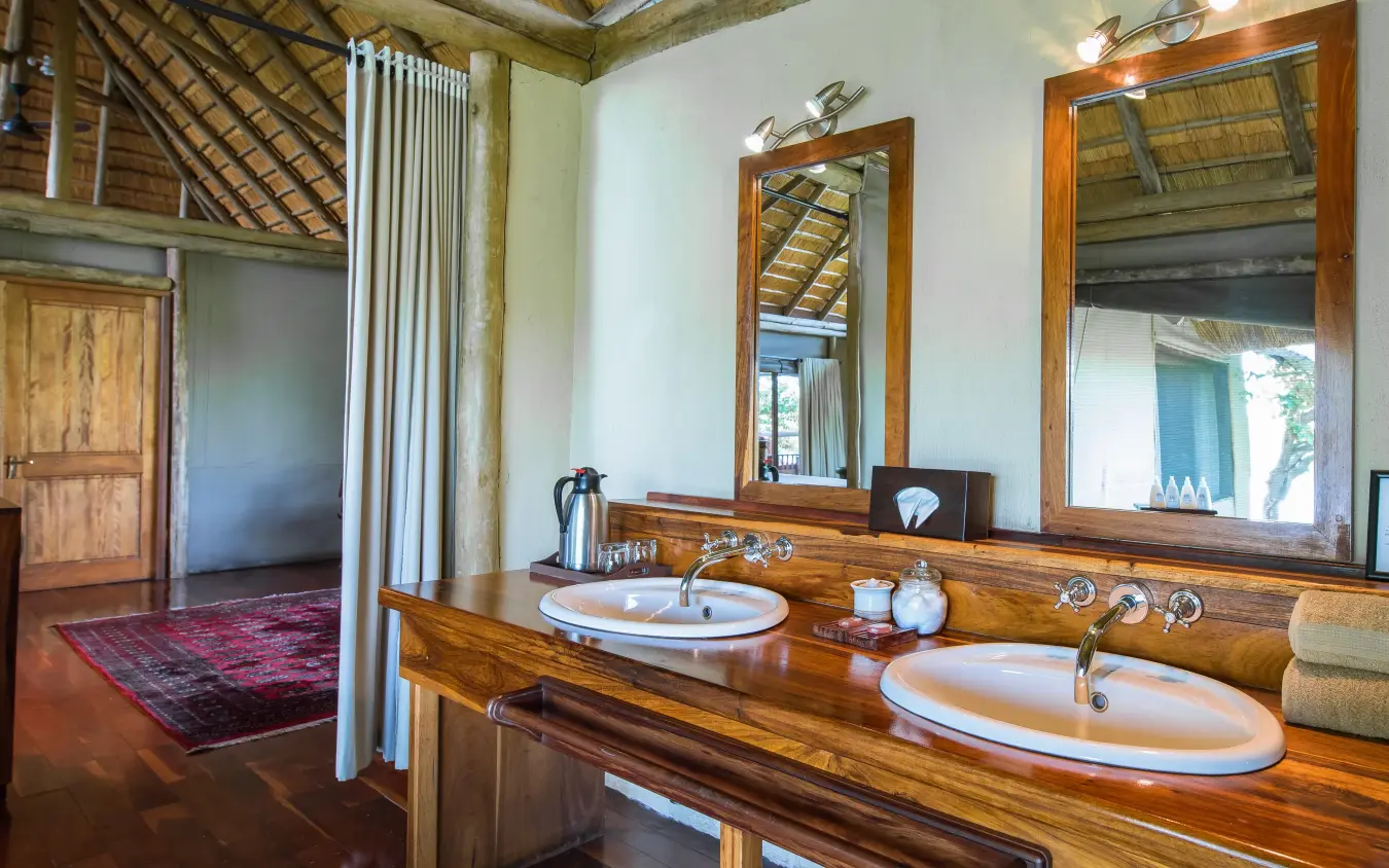 Luxury bathroom with dual wooden vanity and large mirrors in safari lodge, Kwando Lagoon Camp, Linyanti Wildlife Reserve, Botswana