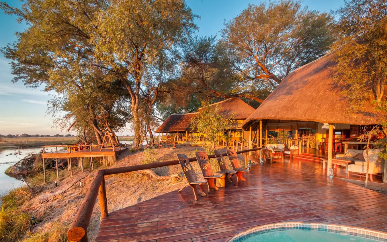 Riverside lodge deck with thatched roof structures at sunset, Kwando Lagoon Camp, Linyanti Wildlife Reserve, Botswana