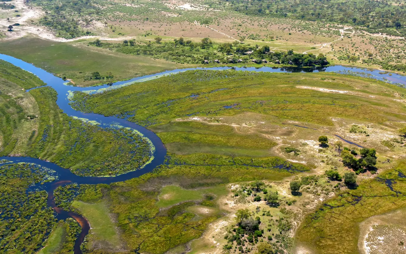 Aerial view of meandering river through wetland grassland with scattered trees, Kwando Lagoon Camp, Linyanti Wildlife Reserve, Botswana