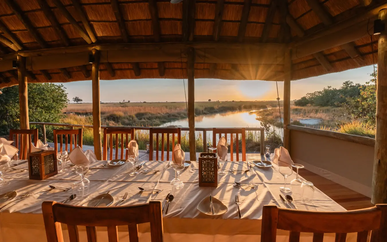 Dining pavilion overlooking wetland at sunset with table settings, Kwando Lebala Camp, Linyanti Wildlife Reserve, Botswana