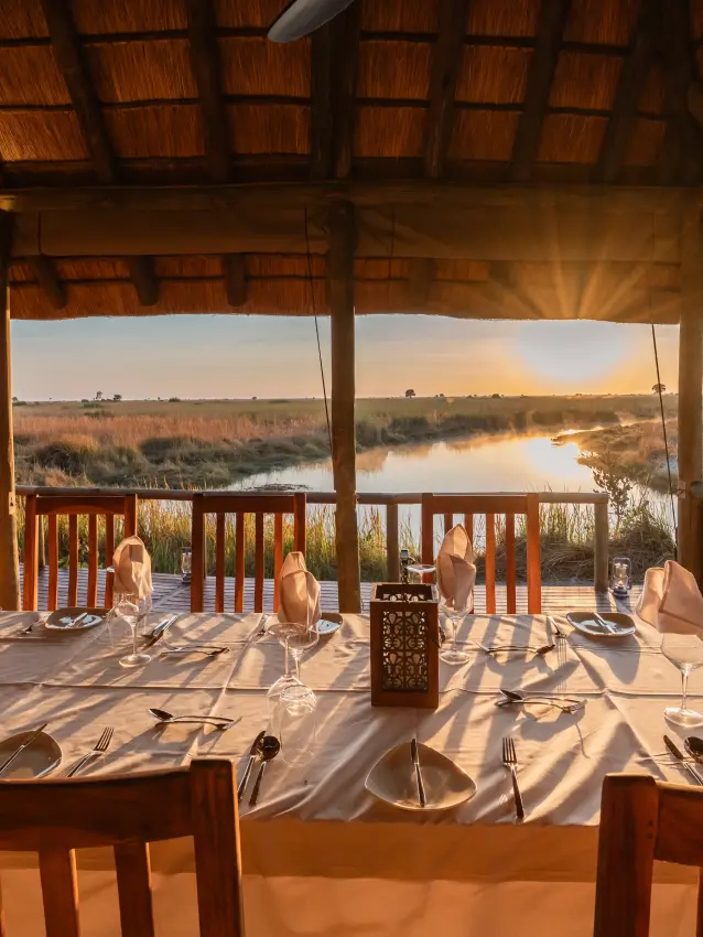 Dining pavilion overlooking wetland at sunset with table settings, Kwando Lebala Camp, Linyanti Wildlife Reserve, Botswana