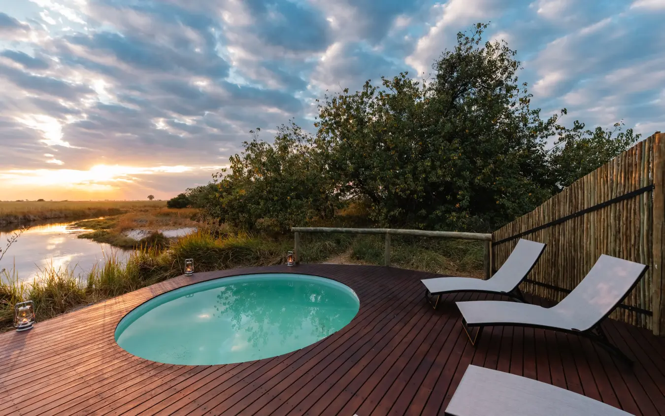 Infinity pool on wooden deck overlooking wetland at sunset, Kwando Lebala Camp, Linyanti Wildlife Reserve, Botswana