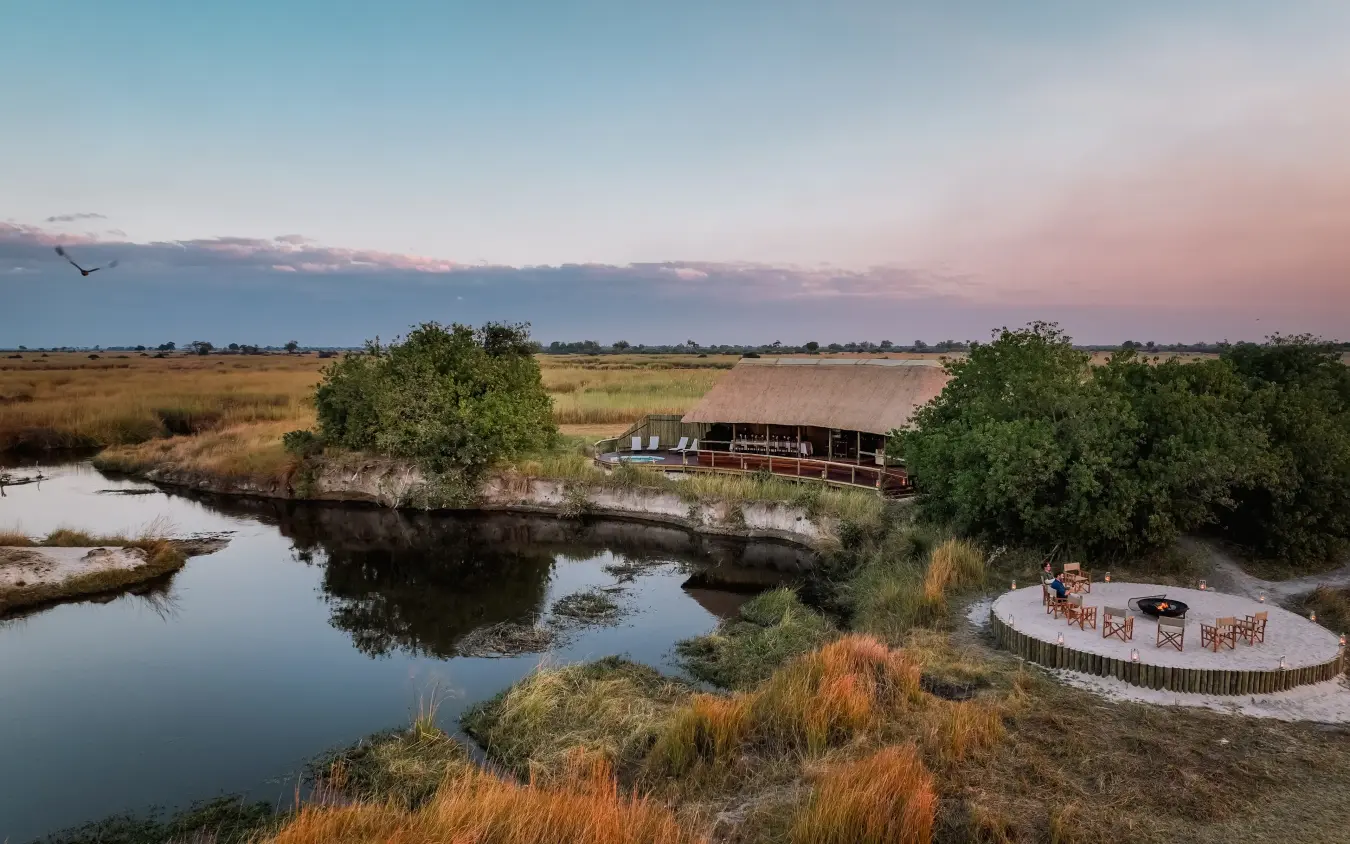 Outdoor dining platform overlooking river at sunset in wetland savanna, Kwando Lebala Camp, Linyanti Wildlife Reserve, Botswana