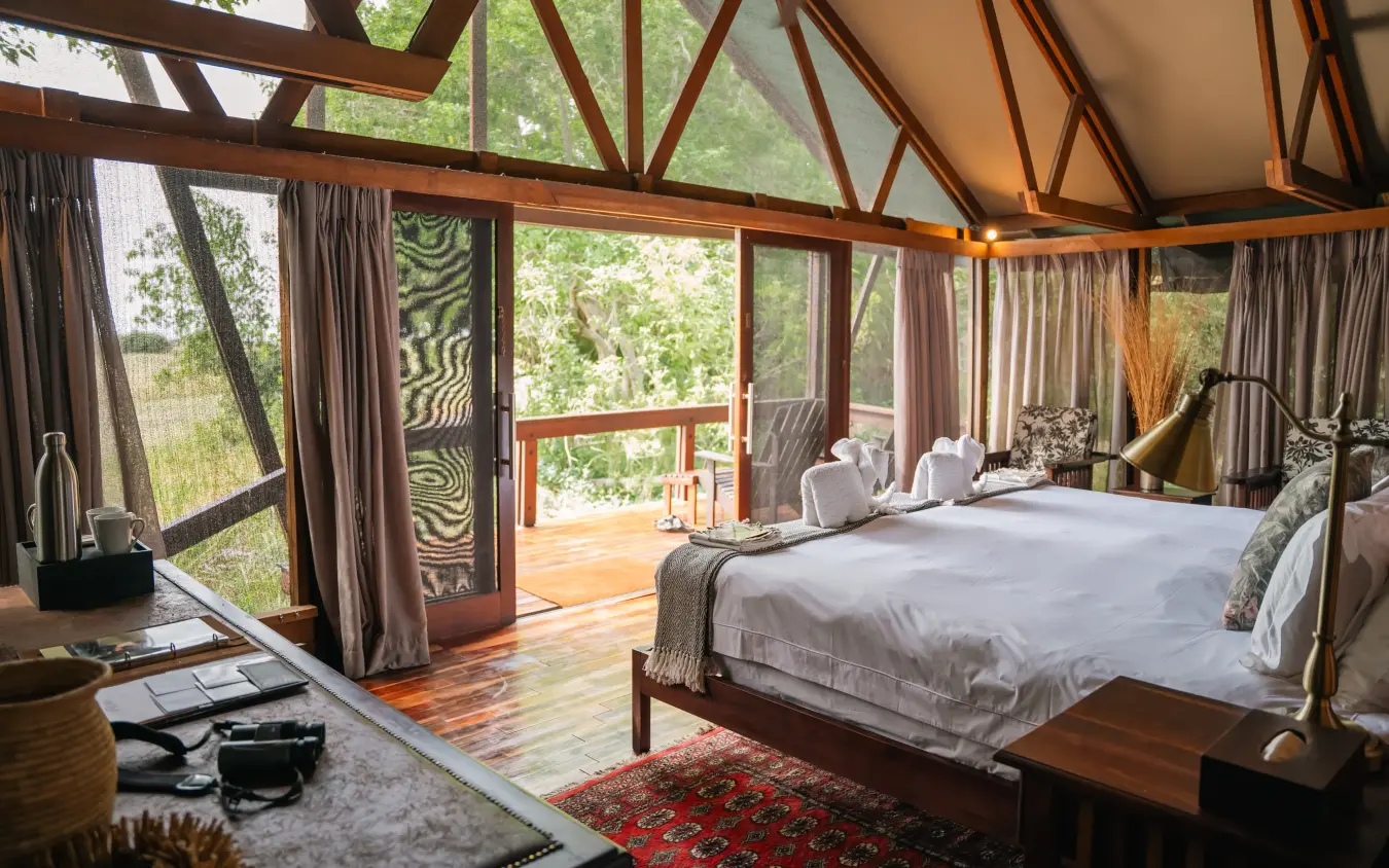 Luxury bedroom tent with wooden bed and panoramic windows overlooking forest, Kwando Lebala Camp, Linyanti Wildlife Reserve, Botswana