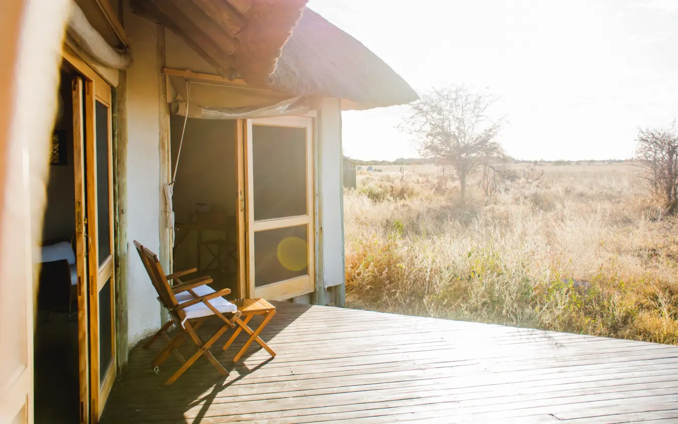 Deck with canvas chair overlooking dry savanna grassland at sunset, Kwando Nxai Pan Camp, Makgadikgadi Pans, Botswana