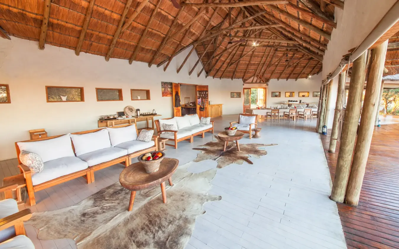 Spacious lodge interior with wooden beams, leather seating and animal hides, Kwando Nxai Pan Camp, Makgadikgadi Pans, Botswana