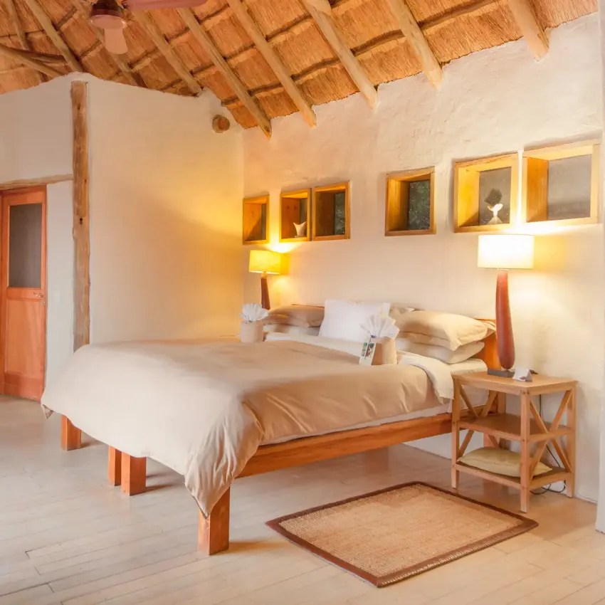 Spacious bedroom with wooden bed frame and thatched roof interior, Kwando Nxai Pan Camp, Makgadikgadi Pans, Botswana