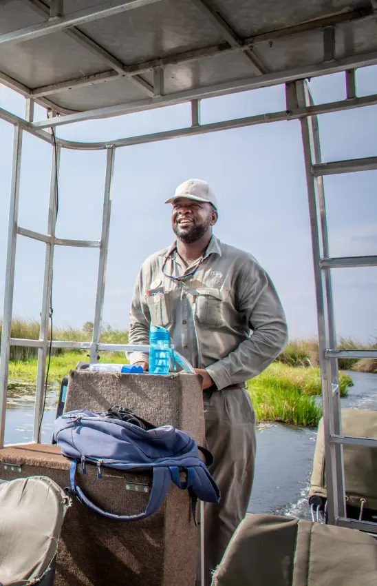 Guide in fishing boat with water landscape behind, Kwando Splash Camp, The Okavango Delta, Botswana