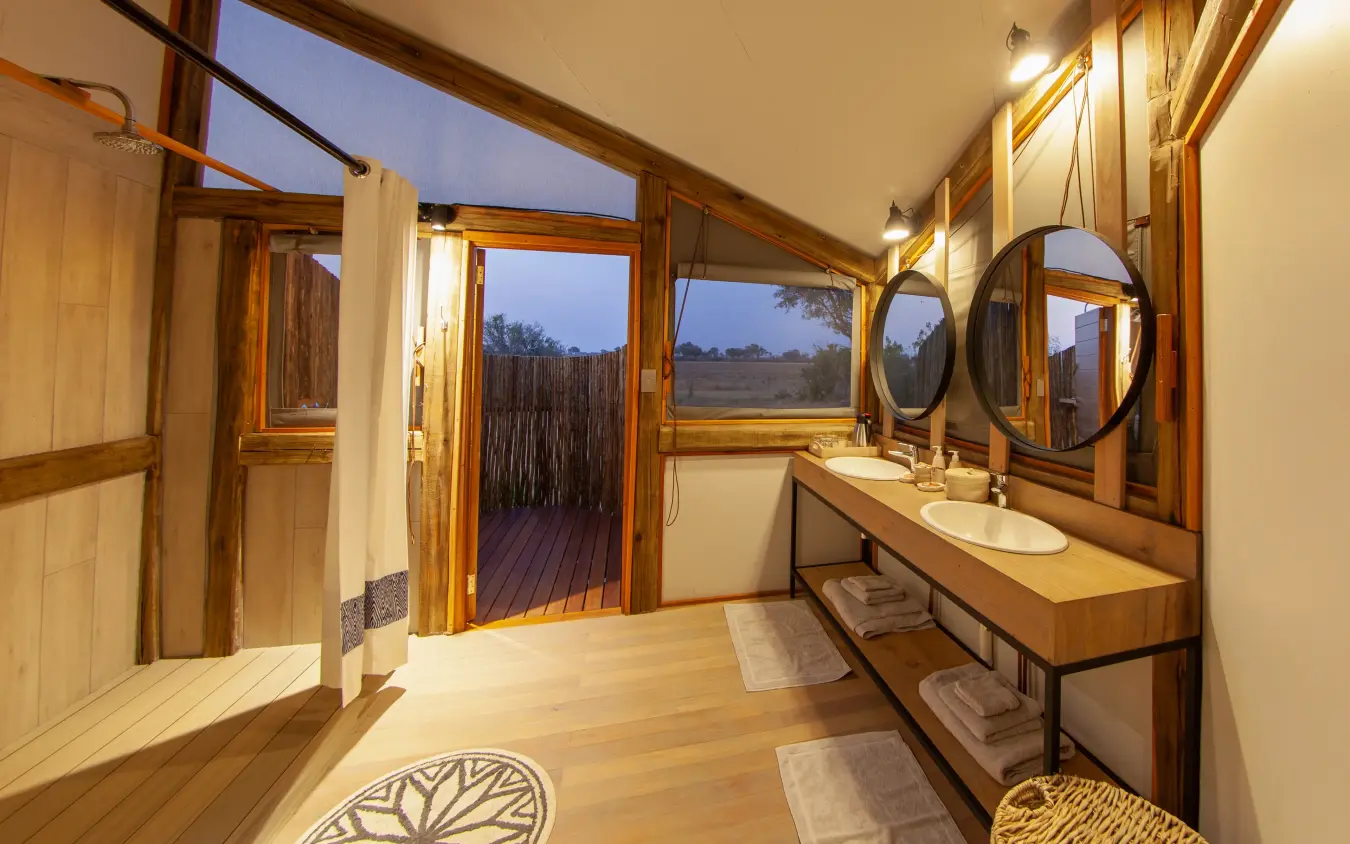 Luxury bathroom with double vanity overlooking rural landscape at dusk, Kwando Splash Camp, The Okavango Delta, Botswana