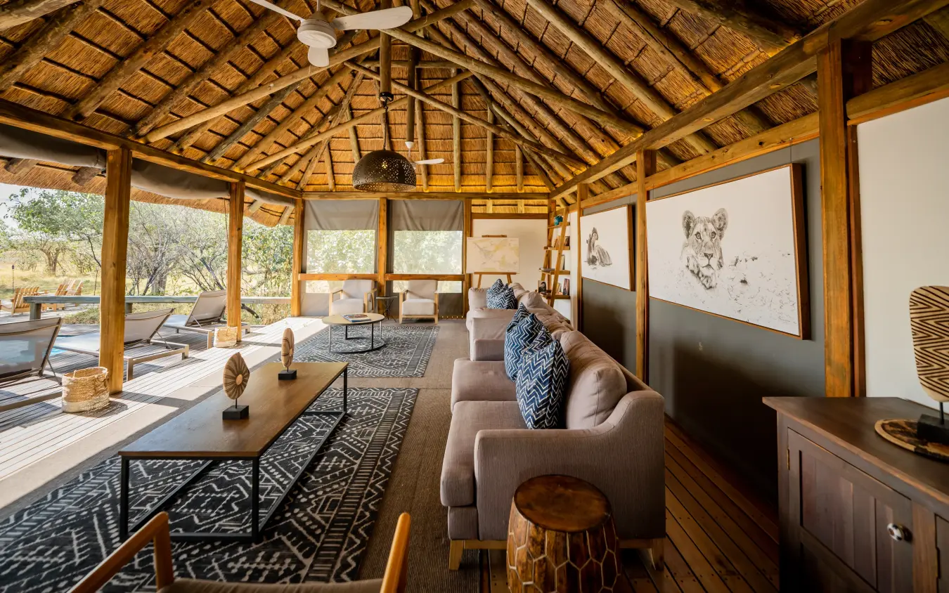 Thatched-roof lounge pavilion with comfortable seating and savanna views, Kwando Splash Camp, The Okavango Delta, Botswana