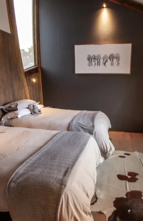 Twin beds in dark bedroom with large window overlooking landscape, Kwando Splash Camp, The Okavango Delta, Botswana