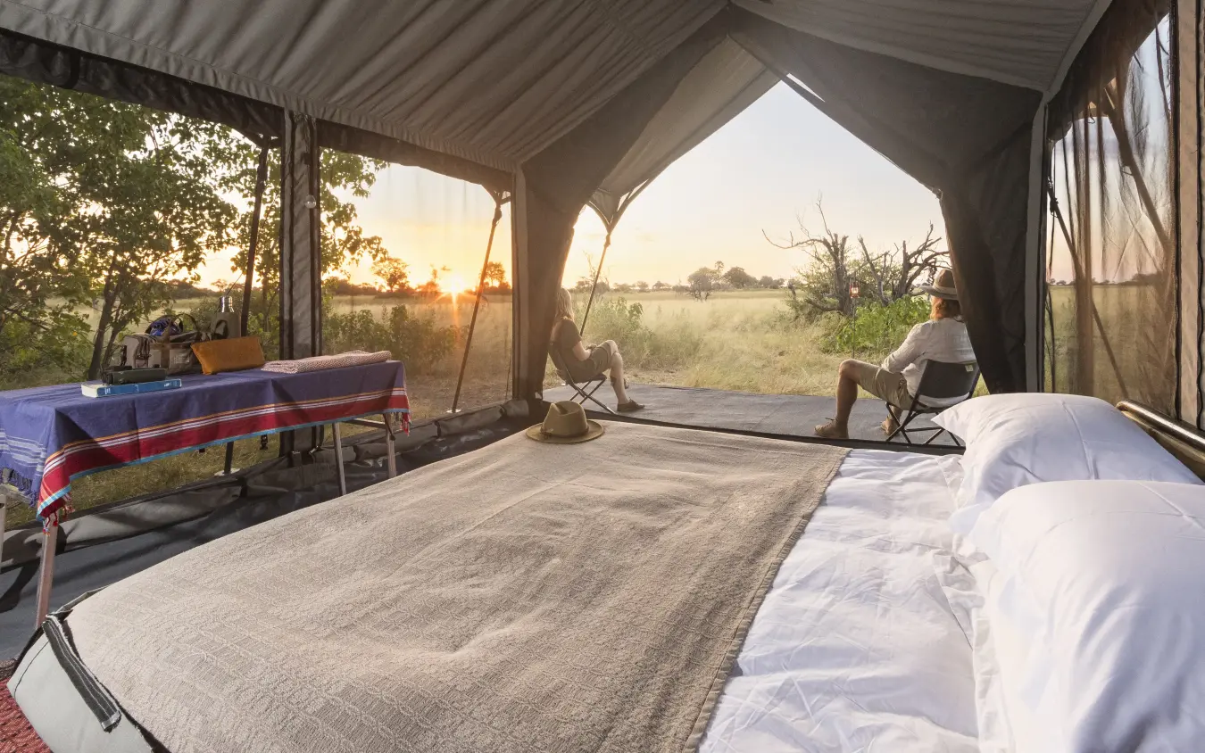 Safari tent interior with beds overlooking savanna landscape, Kweene Trails, The Okavango Delta, Botswana