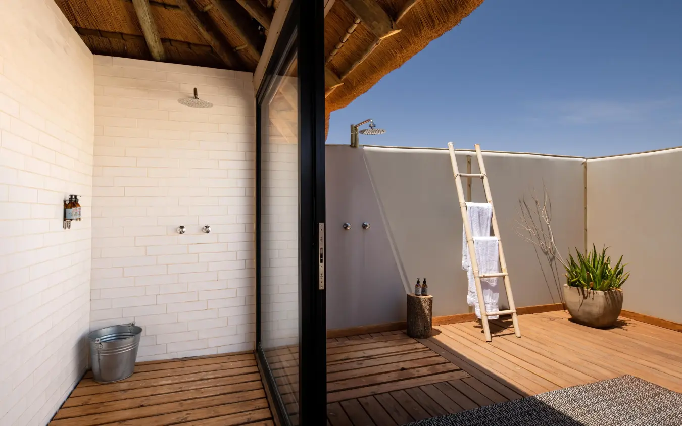 Outdoor shower pavilion with wooden decking and savanna views, Kwessi Dunes, NamibRand Private Reserve, Namibia