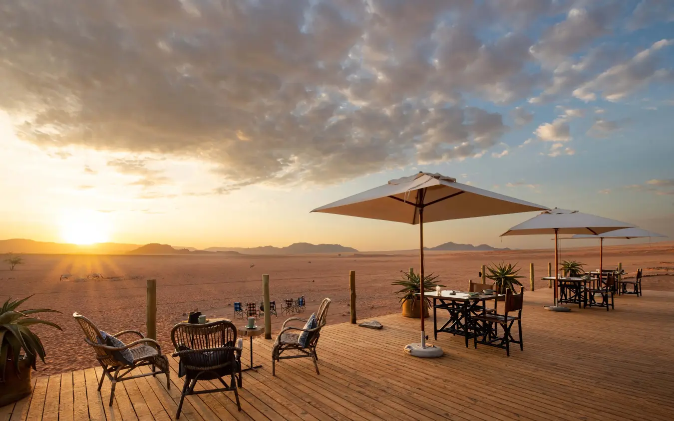 Desert dining deck with umbrellas and tables at sunset, Kwessi Dunes, NamibRand Private Reserve, Namibia